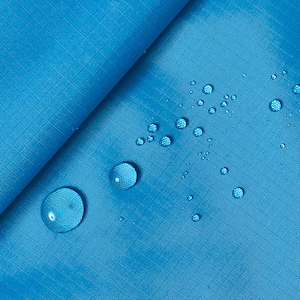 Può includere: Primo piano di un tessuto blu brillante con goccioline d'acqua sulla superficie. Il tessuto è liscio e ha una texture sottile. Le goccioline d'acqua sono trasparenti e rotonde.