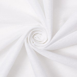 Puede incluir: Tela blanca con una textura lisa, doblada y retorcida en forma de espiral.