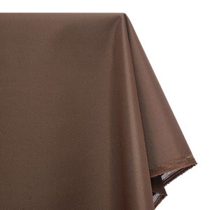 May include: A brown tablecloth with a smooth, slightly shiny surface. The tablecloth is folded in half and the edges are visible.
