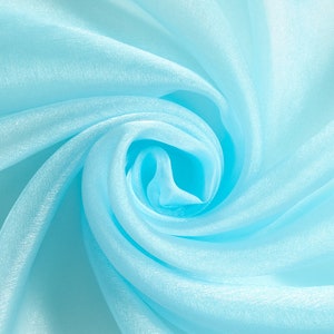 May include: A close-up of a soft, light blue fabric with a swirling, textured pattern. The fabric is sheer and delicate, creating a soft, ethereal look.