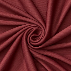 Puede incluir: Primer plano de una tela de color rojo intenso con un patrón de espiral. La tela es lisa y tiene un brillo sutil.