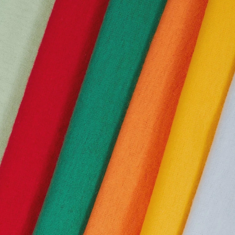May include: A close-up of several fabric swatches in various colors. The colors include light green, red, green, orange, yellow, and white. The fabric appears to be a soft, woven material.