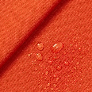 May include: Close-up of a bright orange fabric with water droplets on the surface. The fabric has a woven texture.