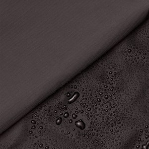 Può includere: Primo piano di un tessuto grigio scuro con finitura idrorepellente. Le gocce d'acqua sono visibili sulla superficie del tessuto.
