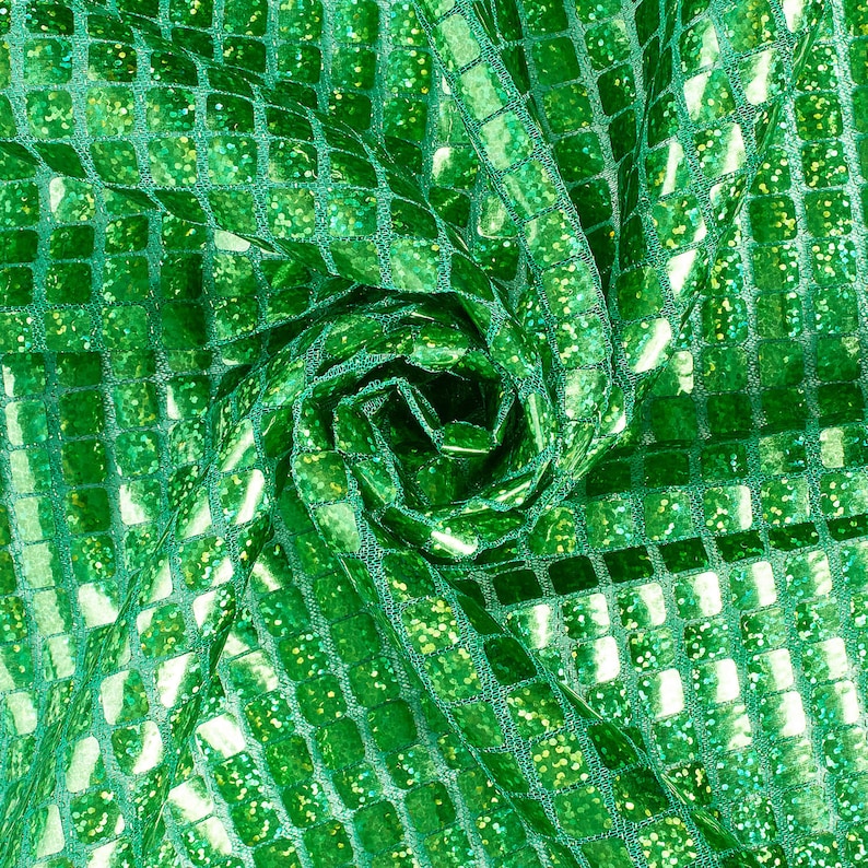 May include: Green fabric with a square sequin pattern. The fabric is folded and twisted, creating a swirling effect.