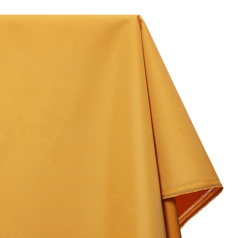 May include: A close-up of a yellow fabric tablecloth with a folded edge. The fabric has a subtle texture and a smooth finish.