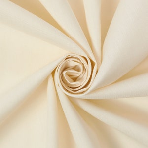 May include: A close-up of a cream-coloured fabric folded into a rose shape. The fabric is smooth and soft, with a subtle sheen.