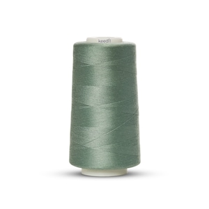 May include: A spool of green sewing thread with the word "keedll" printed on the label.