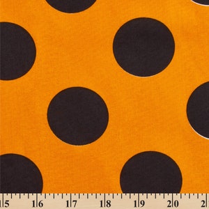 May include: Close-up of orange fabric with large black polka dots. The fabric has a textured appearance and the polka dots are evenly spaced across the surface. The fabric is suitable for various sewing and crafting projects.