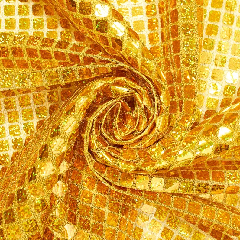 May include: Gold fabric with a square pattern. The fabric is folded and twisted to create a swirling, rose-like shape.
