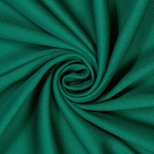 Könnte beinhalten: Nahaufnahme eines tiefgrünen Stoffes mit weicher, glatter Textur. Der Stoff ist gefaltet und verdreht, wodurch ein wirbelndes Muster entsteht.