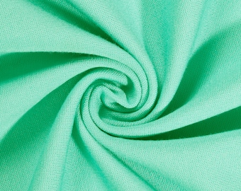 Puede incluir: Primer plano de una tela suave de color verde menta con un patrón de espiral. La tela es lisa y tiene una textura sutil.