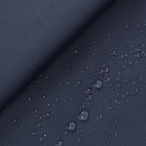 Op de afbeelding: Close-up van een donkerblauwe stof met waterdruppels op het oppervlak. De stof heeft een subtiele textuur.