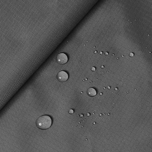Könnte beinhalten: Nahaufnahme eines grauen, strukturierten Stoffes mit Wassertropfen auf der Oberfläche. Der Stoff ist gefaltet und zeigt eine diagonale Falte. Die Tropfen sind klar und rund und reflektieren das Licht. Der Stoff scheint wasserabweisend zu sein.