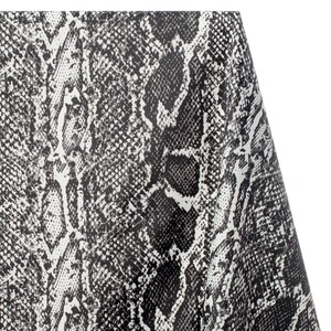 Puede incluir: Primer plano de una tela con estampado de piel de serpiente blanca y negra. La tela tiene una superficie texturizada y un patrón repetitivo de escamas blancas y negras.