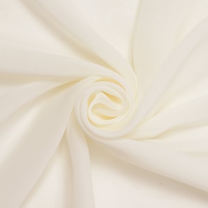 May include: A close-up of a white fabric with a soft, smooth texture. The fabric is draped and folded, creating a swirl pattern.