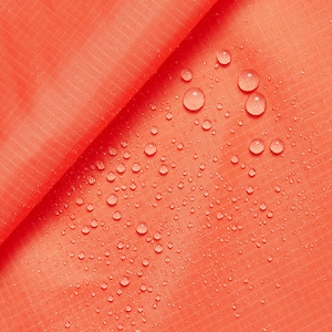 Può includere: Primo piano di un tessuto arancione brillante con gocce d'acqua sulla superficie. Il tessuto ha una texture sottile.