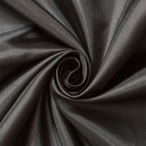 May include: Close-up of a smooth, black fabric with a silky sheen. The fabric is draped and folded, creating a soft, flowing texture.