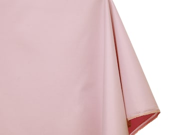 May include: A pale pink tablecloth with a smooth, even texture. The tablecloth is folded in half and the edges are visible.