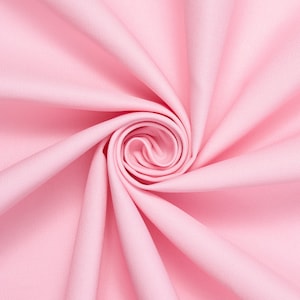 Op de afbeelding: Een close-up van een zachte, roze stof met een draaiende, spiraalvormige print. De stof is glad en heeft een subtiele textuur.