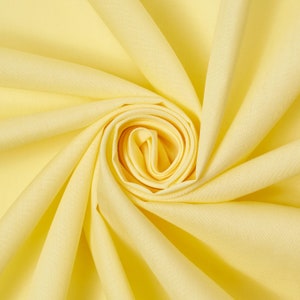 May include: A close-up of a yellow fabric, folded and twisted into a rose shape.