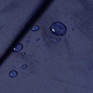 May include: Close-up of a dark blue fabric with water droplets on the surface. The fabric is smooth and has a slight sheen.