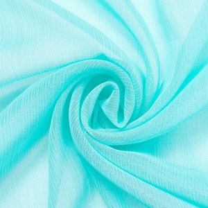 May include: A close-up of a light blue sheer fabric with a textured surface. The fabric is folded and draped to create a swirling pattern.