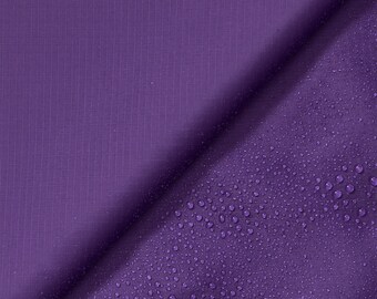 May include: Purple fabric with a textured surface. One side of the fabric is smooth, while the other side has water droplets on it.