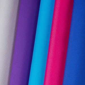 Puede incluir: Primer plano de muestras de tela en varios colores. Los colores incluyen blanco, morado, turquesa, rosa intenso y azul. La tela tiene una textura acanalada.