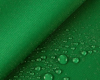 May include: Green fabric with a textured surface. Water droplets are scattered across the fabric.