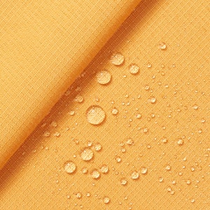 May include: A close-up of a yellow fabric with water droplets on the surface. The fabric has a subtle texture and appears to be water-resistant.