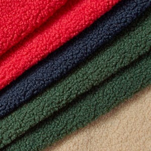 Könnte beinhalten: Nahaufnahme von vier verschiedenfarbigen Fleece-Stoffen. Die Farben sind Rot, Marineblau, Waldgrün und Beige. Das Fleece hat eine strukturierte, flauschige Optik mit sichtbaren Fasern. Die Stoffe sind diagonal angeordnet.