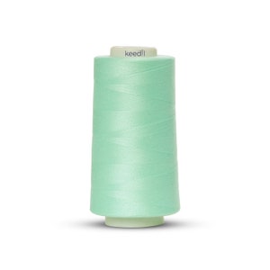 May include: A spool of light green sewing thread with the word "keedli" printed on the label.
