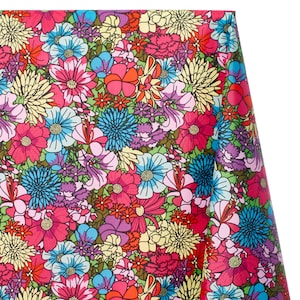 Puede incluir: Primer plano de una tela con un vibrante estampado floral. El diseño presenta una densa disposición de flores coloridas en tonos de rosa, azul, amarillo y morado, sobre un fondo verde. La tela parece estar densamente tejida.