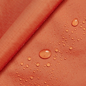 May include: Close-up of a bright orange fabric with water droplets on the surface. The fabric is smooth and appears to be waterproof.