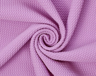 May include: A close-up of a soft, textured fabric in a light purple color. The fabric is folded and twisted, creating a swirling pattern.