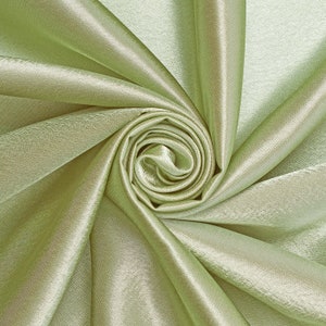May include: A close-up of a soft, light green satin fabric with a swirling, rose-like pattern.