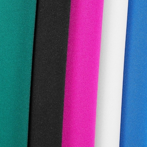 Op de afbeelding: Een close-up van vijf stoffen stalen in tinten van teal, zwart, felroze, wit en blauw. De stoffen hebben een gladde, matte textuur en zijn verticaal naast elkaar geplaatst.