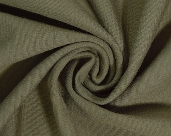 May include: Close-up of a soft, green fabric with a textured surface. The fabric is folded and draped, creating a swirling pattern.