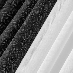 Può includere: Primo piano di tessuto piegato in bianco e nero. Il tessuto è disposto a strisce diagonali, con sezioni alternate di nero e bianco. Il tessuto nero ha un aspetto strutturato e macchiettato, mentre il tessuto bianco è liscio.