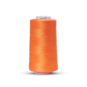 May include: A spool of orange thread with the word "keedli" printed on the label.