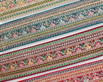 May include: Close-up of several decorative ribbons with intricate embroidered patterns. The ribbons feature a variety of colors, including gold, teal, and red, with floral and geometric designs. The ribbons are ideal for crafting and embellishments.