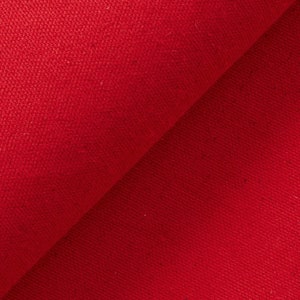 May include: Close-up of a vibrant red fabric with a diagonal fold. The material has a textured surface, suggesting a woven or knitted construction. The bright color and detailed texture are prominent.