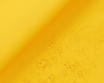 May include: A close-up of a yellow fabric with a diagonal line. The fabric has a textured surface and is covered in small water droplets.