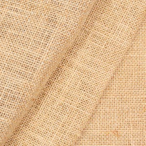 May include: Close-up of a tan burlap fabric with a coarse, woven texture. The fabric is folded, showing the natural fibers and the weave pattern. The material appears to be sturdy and suitable for various craft projects.