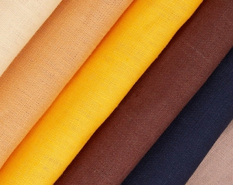 May include: A stack of fabric swatches in various shades of brown, yellow, and beige. The fabric is a smooth, woven material.