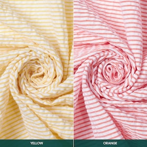 May include: Close-up of two rolled textiles. One is yellow and white striped, the other is orange and white striped. The bottom of the image has the text "YELLOW" and "ORANGE" in a green bar.