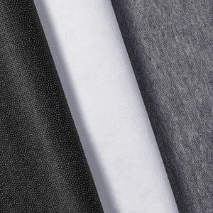 Könnte beinhalten: Nahaufnahme von drei gerollten Stoffen: schwarz, weiß und grau. Der schwarze Stoff hat ein strukturiertes, gepunktetes Muster. Der weiße Stoff ist glatt und dicht gewebt. Der graue Stoff hat eine etwas rauere Textur.