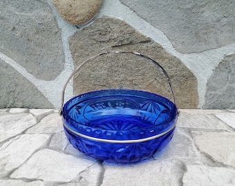 May include: A cobalt blue glass bowl with a silver metal handle. The bowl has a decorative etched pattern and is perfect for serving snacks or candy.