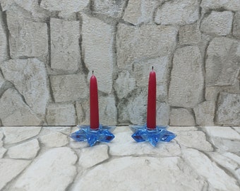May include: Two blue glass star-shaped candle holders with red candles.